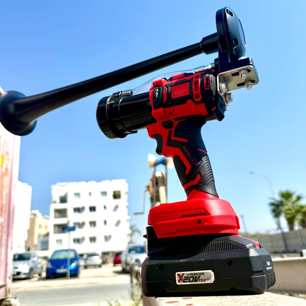 Battery-powered train horn on a red Xcore tool battery outdoors