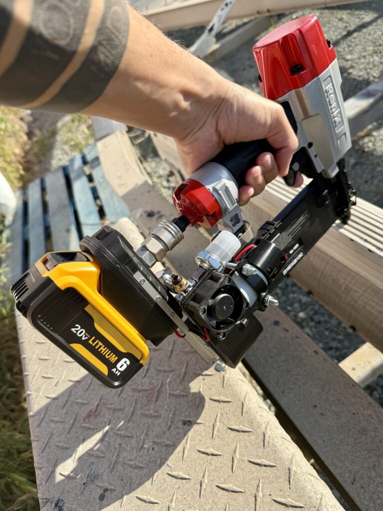 Hand nailing into a wooden board with a nail gun powered by the cordless mini compressor