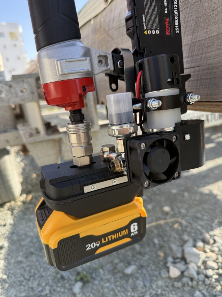Mini compressor powering a nail gun on a yellow 20V battery outdoors