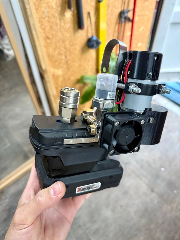 Hand holding the cordless mini compressor on a black Xcore battery
